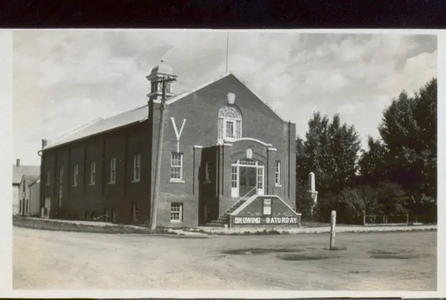 Brick movie theatre with "Showing Saturday" sign